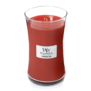 Woodwick sveća crvene boje sa mirisom cimeta u staklenoj posudi.